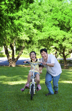 父親教兩個小女孩騎自行車