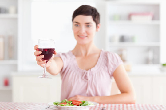 微笑的黑發(fā)女人喝葡萄酒