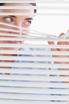 漂亮的女商人通過百葉窗偷看