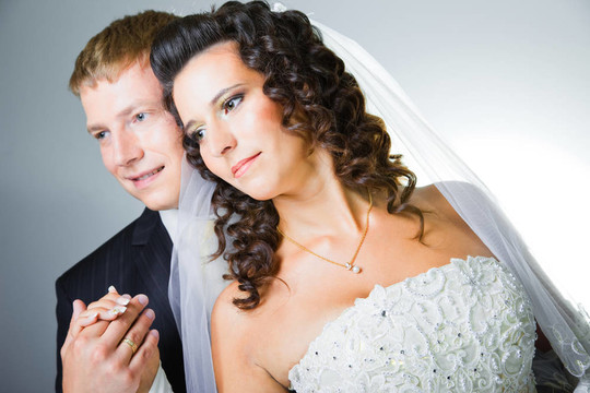 年輕優(yōu)雅的迷戀剛結(jié)婚的新娘和新郎抱著灰色背景的工作室肖像