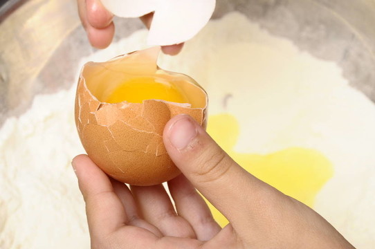 小孩把雞蛋掰成面粉