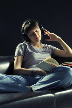 放松的年輕女性聽音樂和看書