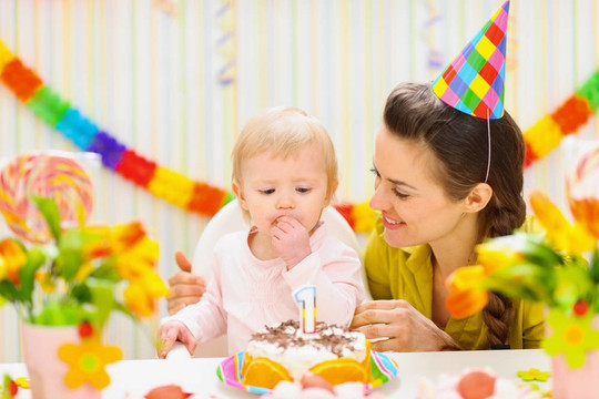 快樂媽媽和嬰兒吃生日蛋糕肖像