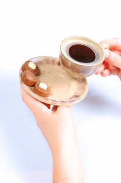 果仁巧克力；杯；黑咖啡和女性手上白色