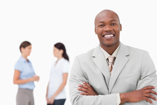 微笑的推銷員，雙臂交叉，背后有伙伴