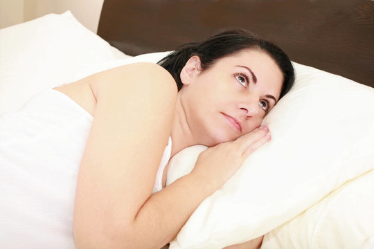 一個(gè)年輕女子躺在床上醒著。不眠沉思。