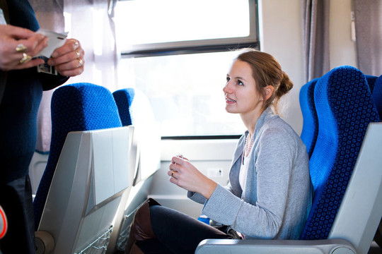 年輕女子乘火車旅行；火車票由火車售票員檢查