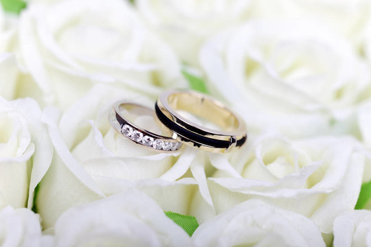 白玫瑰花束上的兩枚結婚戒指。