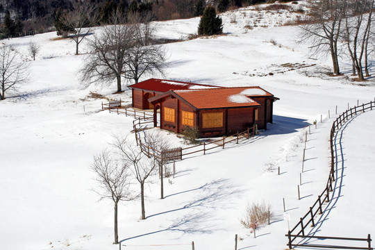 在覆蓋著雪的草地中間孤立的小山小屋
