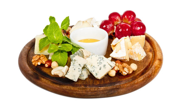各种带蜂蜜的奶酪；盘子上的坚果和葡萄；在白色上分离