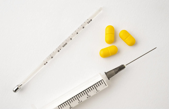 具有白色隔離藥丸的醫(yī)用注射器和體溫計(jì)