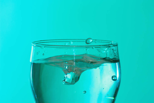 在綠松石光飛濺的新鮮冰水玻璃