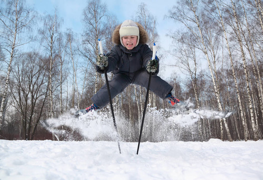 小男孩與越野滑雪板和桿的跳躍和舌頭