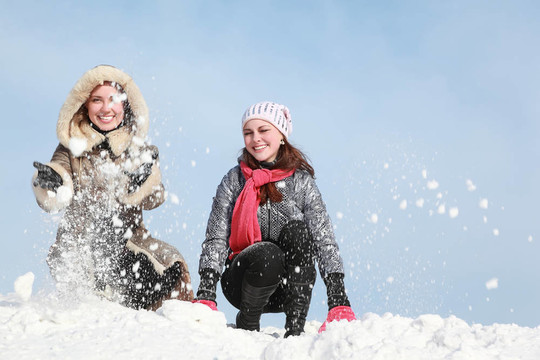兩個年輕女子蹲著扔雪