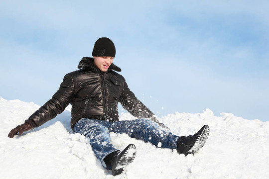 青年坐在冬天的雪地上，把他扔了起來