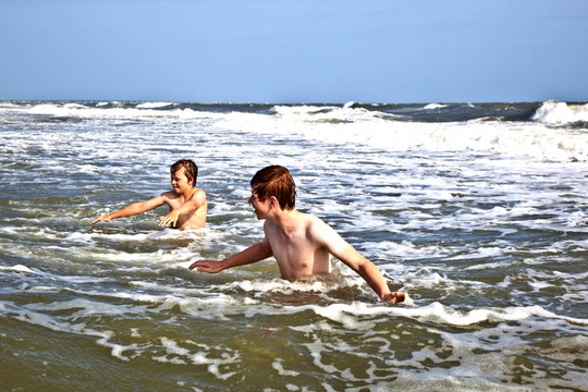 在狂野海洋中享受波浪的男孩