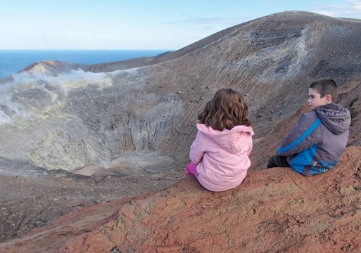 女孩和男孩坐在弗卡諾島的西西里島附近的火山口邊緣；意大利