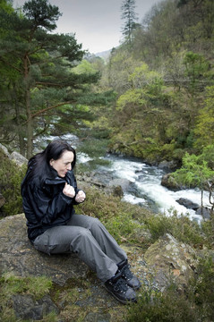 女性旅行者靠近河的感覺冷