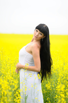漂亮的夏天女人在Yellow Rape Flowers
