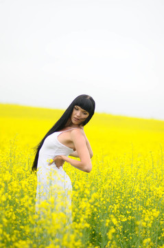美麗的女人在黃色油菜田