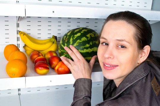 一个女人在市场上买水果的形象。