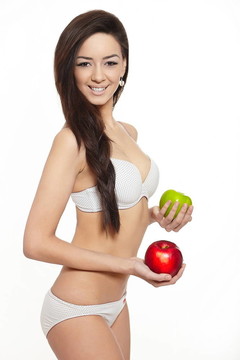 美麗的微笑的黑發(fā)白衣女人內(nèi)衣用綠色和紅蘋果飲食孤立在白色的肖像