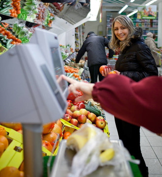 美丽的年轻妇女在杂货店/超市生产部买水果和蔬菜