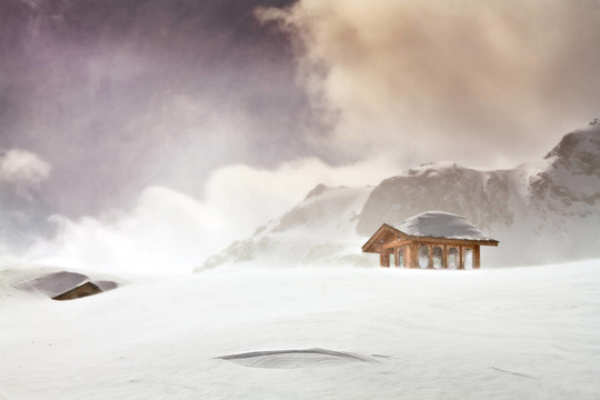 木制小屋，白雪覆蓋的小屋在暴雪在雪山山頂?shù)娘L(fēng)景照片