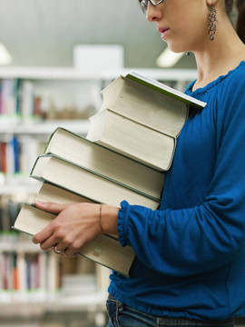 在圖書館婦女拿著一堆書
