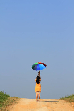 美麗的女人拿著五顏六色的傘和藍色的天空