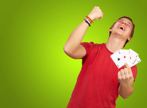 年輕人做一個勝利者手勢在綠色上玩撲克的肖像