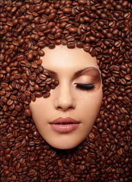 一个女孩的脸淹没在咖啡豆明亮的棕色化妆闭着眼睛的女孩在咖啡