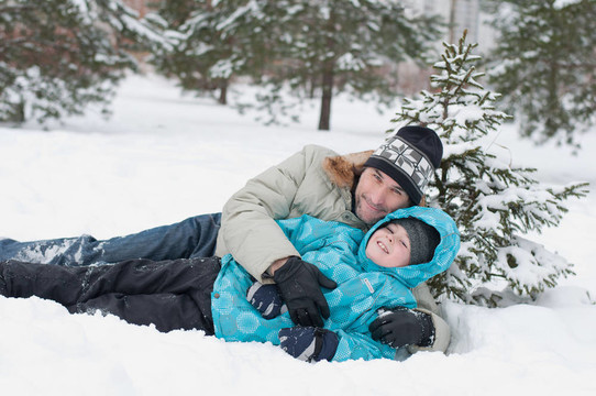爸爸和兒子在公園里的雪地里休息