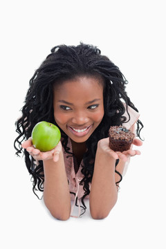 一个面带微笑的年轻女子手里拿着一个苹果和一个小圆面包