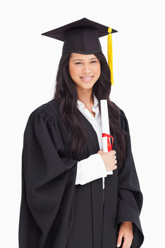 一個面帶微笑的女人拿著學(xué)位，因為她已經(jīng)大學(xué)畢業(yè)了