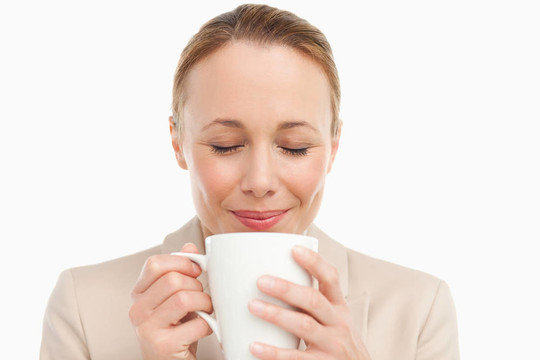 穿著西裝的女人聞著她的茶