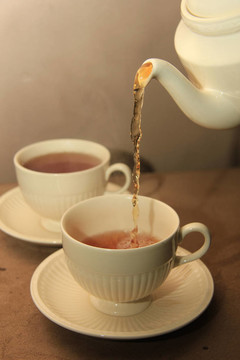 在經(jīng)典的白色茶杯倒茶
