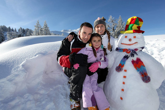 夫婦與孩子在雪人旁邊的山度假村