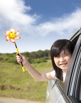 快樂的小女孩在車里抱著風車