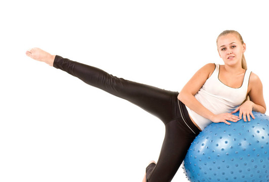 年轻女子在健身房与一个蓝色的球