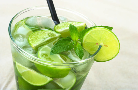 朗姆雞尾酒Mojito；石灰；薄荷和冰塊的照片上的砂（選擇性聚焦；對(duì)薄荷葉和輪圈上的石灰層上部的焦點(diǎn)