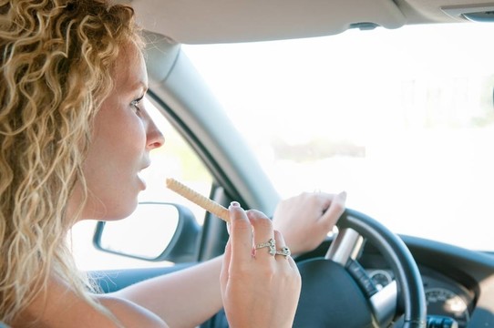 年輕女子邊開車邊吃甜食