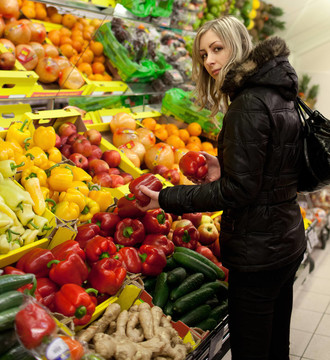 漂亮的年轻女人在超市买水果和蔬菜