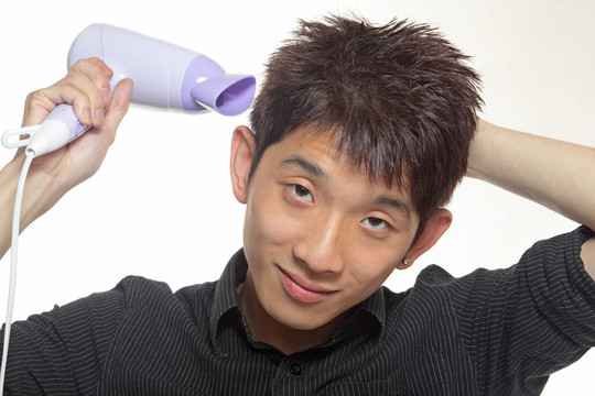 都市潮男，一個年輕的男性使用吹風(fēng)機將頭發(fā)很好的理念形象