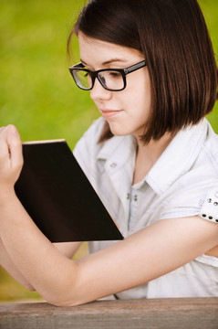 可愛(ài)的女孩戴著眼鏡閱讀有趣的書(shū)