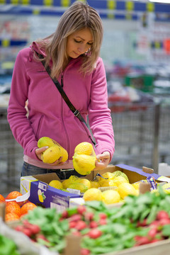 美丽的年轻妇女在杂货店/超市生产部买水果和蔬菜
