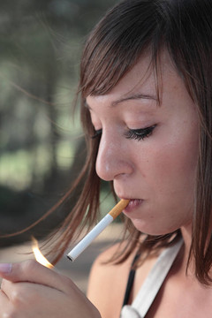 一個漂亮的年輕女人在戶外點燃香煙的肖像