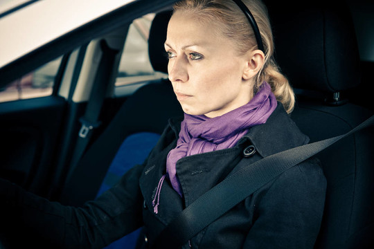 女人坐在車里，眼睛盯著路