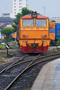 紅黃柴油機(jī)車列車接近曼谷火車站，垂直于中國(guó)的火車站；垂直于中國(guó)的火車站，靠近中國(guó)的火車站。