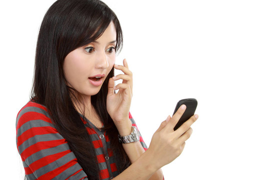 一個驚訝的可愛的年輕女人在她的手機(jī)上發(fā)了一條短信。